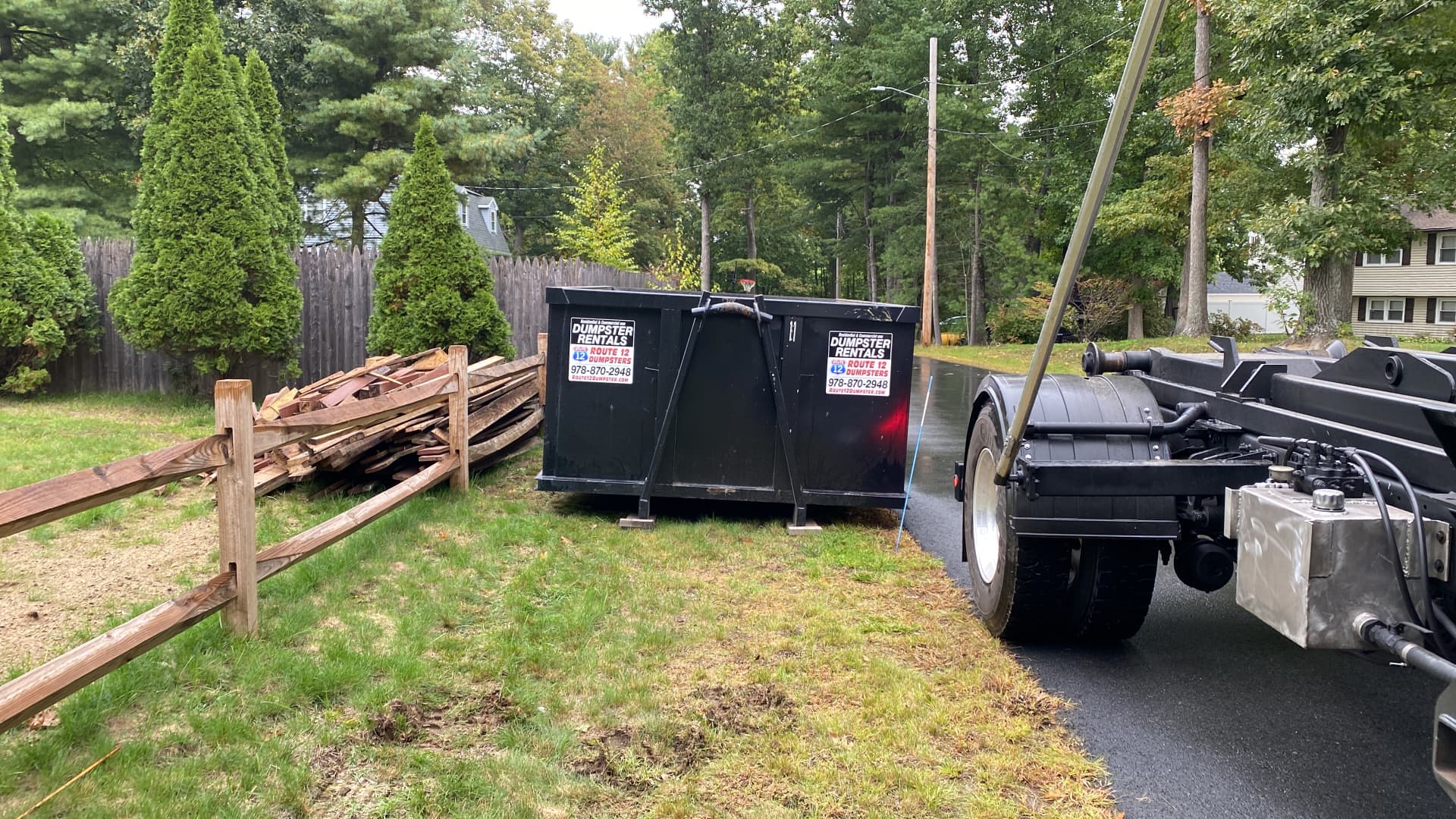 Route 12 dumpster dropped beside a yard with wood debris