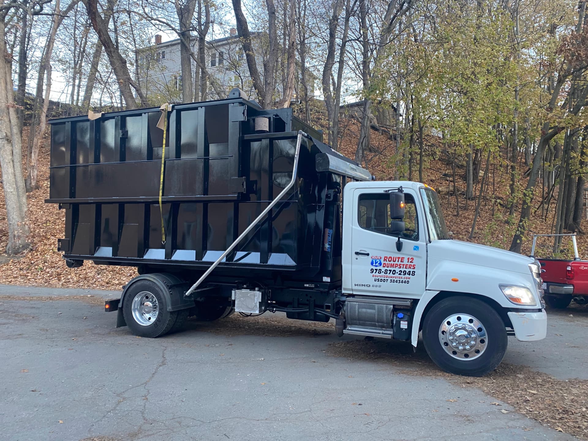 Route 12 Dumpsters truck carrying a black roll-off dumpster